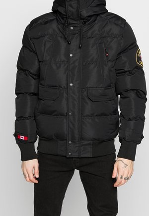 Sort polstret jakke med trykknapper, forlommer, patch med det canadiske flag på ærmekanten og broderet patch på overarm.