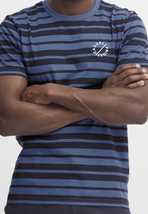 Stribet kortærmet t-shirt i marineblå og blå, med rund halsudskæring og et hvidt trykt logo på brystet. Bomuldsstof.