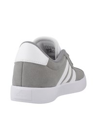 Zapatilla gris de ante con detalles blancos, que cuenta con una suela de goma lisa, tres franjas blancas y un cuello acolchado para mayor comodidad.