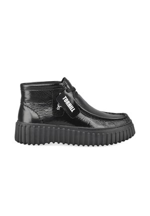 Black shiny leather ankle boot with thick ribbed sole, lace closure, and tag reading "TORHILL" on the side.