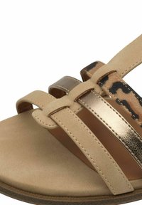 Sandalias beige con tres tiras metálicas doradas y un acento de estampado de leopardo. Suela plana con textura similar al ante y detalles de costura en contraste.