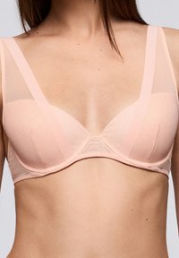Sostenedor con aros en suave tela rosa con tirantes de malla transparente. Presenta copas lisas con una costura en el centro y una banda sólida por debajo.