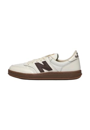 Zapatilla blanca de perfil bajo New Balance con suela marrón y logo "N" en marrón oscuro en el lateral, mostrada en vista de perfil sobre fondo blanco.