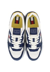 Sneakers navy e bianchi con finitura in pelle liscia, punta arrotondata, dettagli perforati e accenti di logo in rosso e blu sulla linguetta.