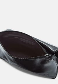 Pochette nera in pelle con una superficie liscia, chiusura con zip e fodera scura. Presenta un marchio discreto e una base rotonda per garantire stabilità.