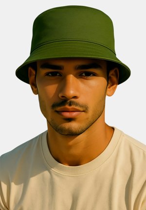 Man with trimmed beard wearing an olive green bucket hat and beige crew neck shirt, facing forward with neutral expression.