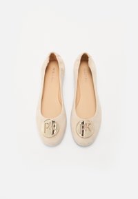 Ballerines en cuir suédé beige avec un bout arrondi, une semelle intérieure rembourrée et un accent logo doré circulaire sur le devant.