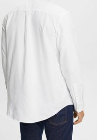 Weißes Langarmhemd mit Knopfleiste, im lässigen Schnitt und mit glatter Textur, kombiniert mit dunklen Jeans.