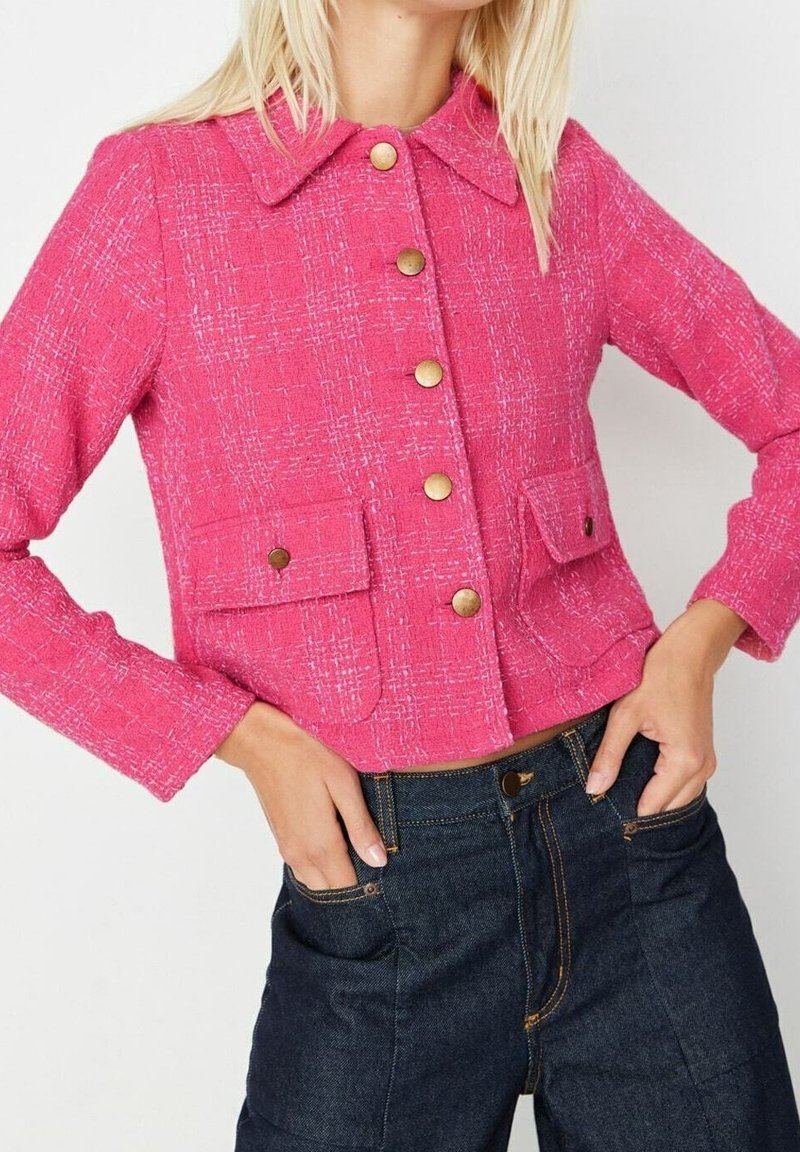 Roze tweed cropped jack met een kraag, voorzien van gouden knopen, twee klepzakken en een gestructureerde stof, gecombineerd met donkerdenim broek.