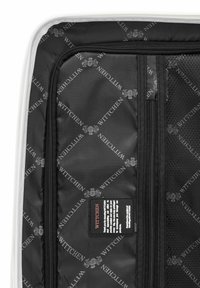 Interior de equipaje negro con un patrón de logo, compartimento con cremallera y etiqueta de marca. Tejido suave con un diseño moderno.