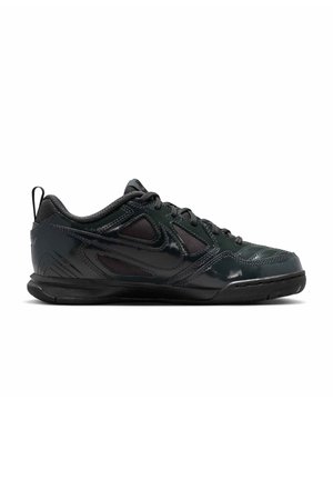 Chaussure de sport basse noire avec lacets à l'avant, tige en mesh et synthétique, semelle extérieure en caoutchouc texturé sur fond blanc.
