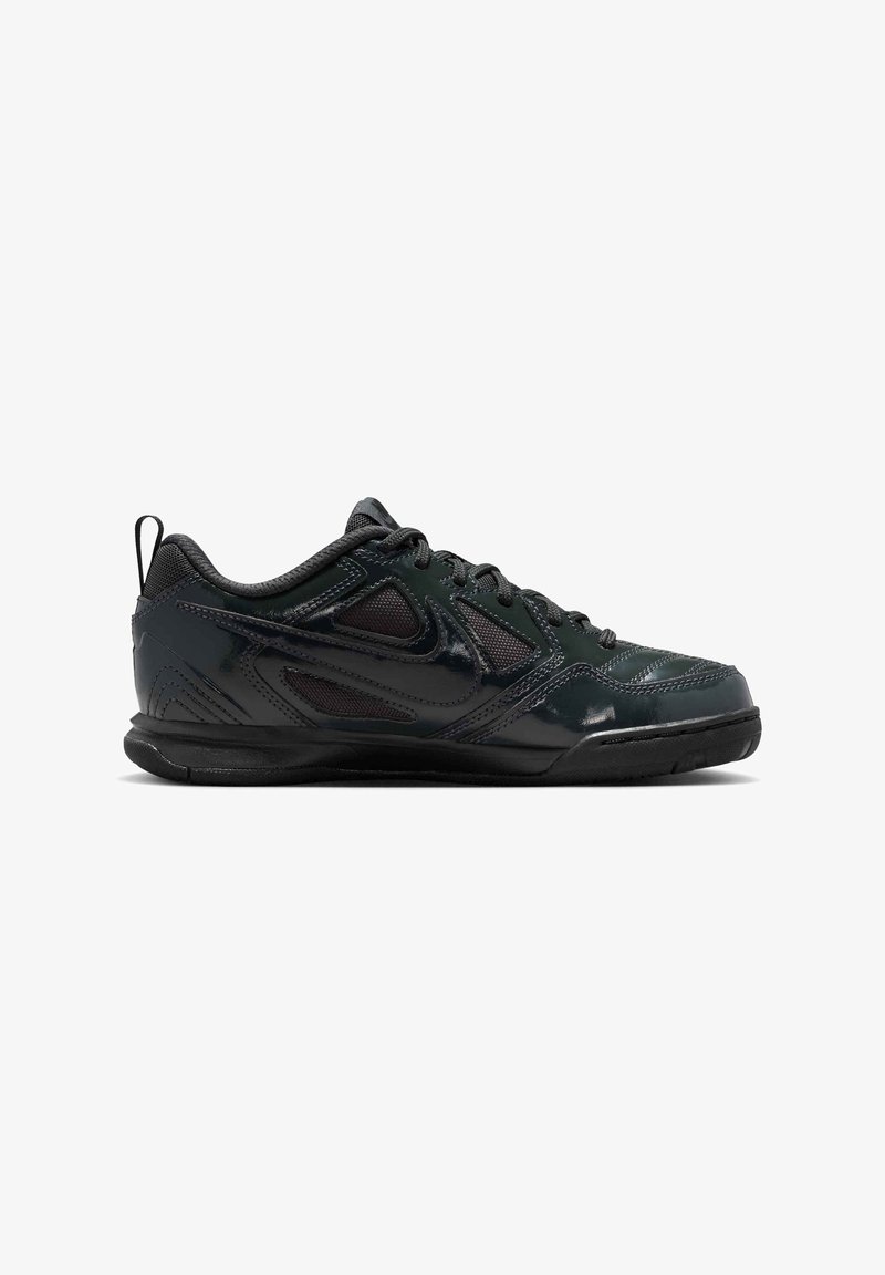 Chaussure de sport basse noire avec lacets à l'avant, tige en mesh et synthétique, semelle extérieure en caoutchouc texturé sur fond blanc.