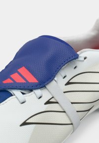 Bela športna obutev z modrim sintetičnim zgornjim delom s teksturiranim vzorcem, rožnatim poudarkom, sivimi vezalkami in oblikovanim vzorcem na strani.