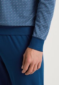 Blauwe sweatshirt met een geometrisch patroon; aansluitende boorden en tailleband; zachte stofkwaliteit, gecombineerd met effen blauwe joggers.