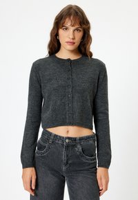 Cardigan accorciato grigio carbone realizzato in tessuto morbido, con scollo rotondo, maniche lunghe e chiusura con bottoni sul davanti.