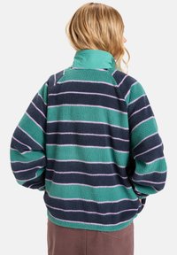 Fleecasti pulover s visokim ovratnikom, s prugastim uzorak u tirkiznoj, tamnoplavoj i lavandi. Mekan materijal i oversized kroj.
