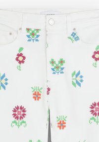 Witte stof jeans met meerkleurige bloemenborduursels in rood, groen, blauw en geel. Bevatte een gemarkeerde knop en details van een metalen rits.