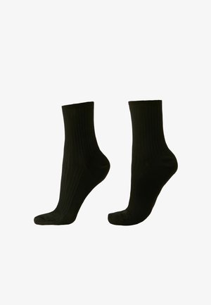 Chaussettes noires côtelées de hauteur mi-mollet, avec une texture lisse et des renforts au niveau des orteils et du talon pour une durabilité accrue.