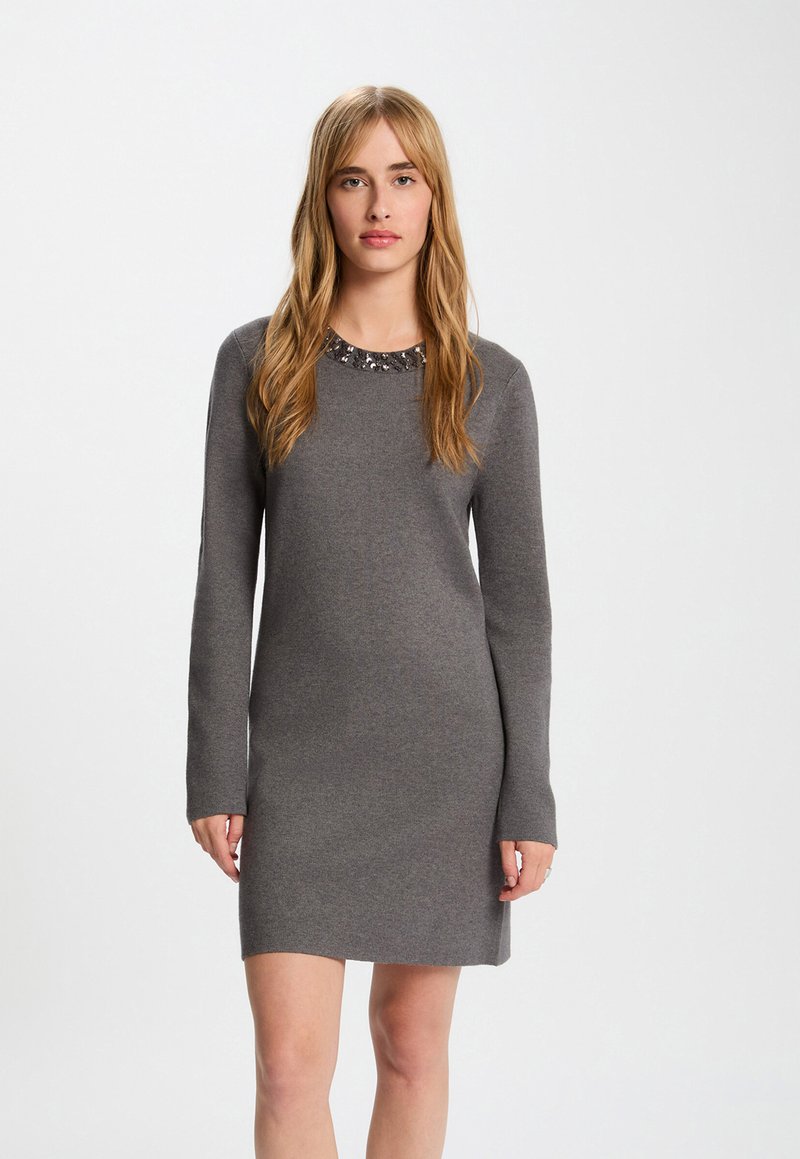 Graues Langarmkleid aus weichem Stoff, mit einem runden Ausschnitt, der mit Verzierungen geschmückt ist. Einfaches, figurbetontes Design.