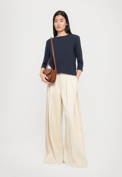 Maglietta a maniche lunghe navy, pantaloni a palazzo plissettati crema, borsa a spalla marrone, design minimalista, morbida texture del tessuto.
