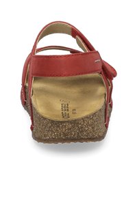 Rød lædersandal med korksål, justerbare stropper og en tekstureret fodseng. Den har en afrundet tå og et komfortabelt design.