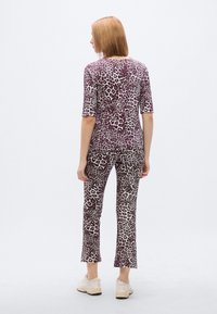 Τοπ με λεοπάρ σχέδιο και κοντά μανίκια, με αντίστοιχο στενό παντελόνι. Και τα δύο έχουν απαλτή υφή σε αποχρώσεις του μοβ και εκρού. Περιλαμβάνονται και casual παπούτσια.