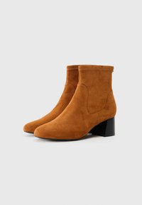 Suede enkellaarzen in een warme bruine kleur, met een spitse neus, een middelgrote blokhak en minimale stikseldetails.