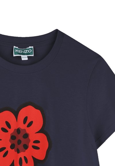 T-shirt en coton bleu marine avec un grand motif de fleur rouge et des détails noirs, col rond et manches courtes.