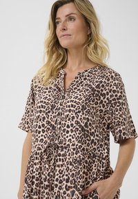 Rochie cu imprimeu leopard dintr-un material ușor, cu închidere prin nasturi, manșon scurt, talie cu șnur și croială lejeră.