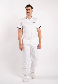 Weißes Sportset mit einem kurzärmeligen Shirt mit marineblauen Akzenten und rundem Kragen, kombiniert mit Jogginghosen im Jogger-Stil mit elastischem Bund.