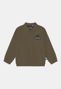 Casaco leve verde-oliva com fecho de correr, dois bolsos laterais, punhos elásticos e um logótipo do Jurassic World bordado no peito.