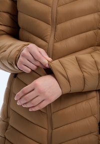 Bruine, gewatteerde pufferjack met een rits en een strakke manchetontwerp met een gladde textuur, met gedetailleerde stiksels.