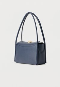 Majhna temno modra usnjena ročna torbica z zaobljenim poklopcem in zlatim zaponkom, opremljena z dvema dolgima ročajema in oblikovano pravokotno osnovo.