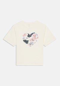 Kurzärmliges cremefarbenes T-Shirt mit einem Herzdesign aus mehrfarbigen Pailletten in Pink, Grau und Blau. Klassischer Rundhalsausschnitt.