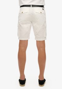 Bermudas blancas de carga con una tela texturizada, que cuentan con bolsillos laterales, una cinturilla ajustada y detalles en botones de tono dorado.
