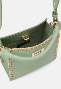 Borsa a tracolla in pelle verde con hardware dorato e accenti intrecciati beige lungo i bordi. L'interno presenta una fodera liscia.