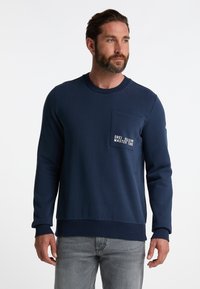 Felpa navy in misto cotone, con maniche lunghe, colletto rotondo, tasca frontale e testo ricamato bianco sulla tasca.