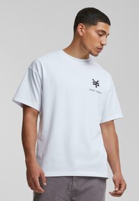 Hvid bomulds t-shirt med korte ærmer, prydet med et sort Zoo York logo på venstre bryst. Enkel, klassisk design med en afslappet pasform.