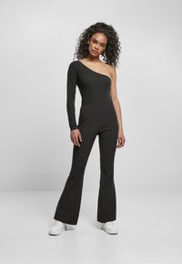 Svart one-shoulder bodysuit kombinert med høytlivede svart og hvit stripete flared bukser. Hvite sneakers fullfører antrekket.