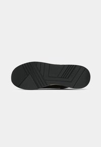Suela de zapato de goma negra con patrones de agarre texturizados, que presentan líneas diagonales y bordes curvados, diseñados para ofrecer tracción y durabilidad.