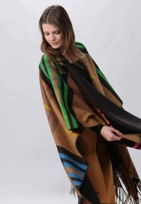 Poncho multicolore avec un mélange de rayures brunes, vertes, bleues et roses, orné de franges le long des bords. Tissu doux et texturé.