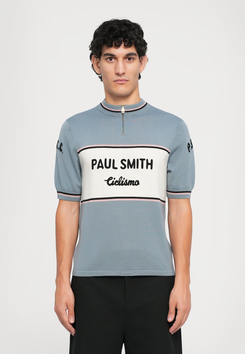 Polo de punto de manga corta en azul claro, con cuello con cremallera, logotipo en negrita "PAUL SMITH" y una banda contrastante con "Ciclismo" en negro en el pecho.