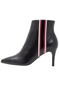 Musta nahkainen nilkkuri, jossa on terävä kärkki ja korkea stiletto-korko, ja sivuilla on punaisia, valkoisia ja mustia raitoja. Suora pinta.