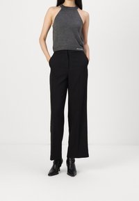 Grå halterneck-top med små dekorationer, parat med svarta vida byxor och spetsiga svarta ankellånga stövlar.