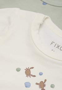 Vit bomull t-shirt med krabba och snäcka i tryck i brunt, blått och grönt. Har rund halsringning och korta ärmar.