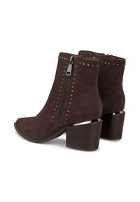 Botas de tobillo de ante marrón con cremallera lateral, tachuelas plateadas a lo largo de la costura y un tacón apilado con textura similar a la madera.