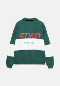 Felpa verde e bianca con grande testo rosso "STWD", dotata di colletto, vestibilità oversized e polsini a coste. Il testo include "New School Gen" e l'anno.