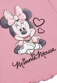 Różowa koszula z krótkim rękawem z grafiką Myszki Minnie z kokardą, serduszkami oraz napisem "Minnie Mouse" w czarnym kursywie.