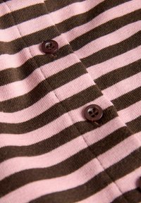 Material cu dungi orizontale maro și roz, cu doi nasturi maro închis cusuti pe țesătură.