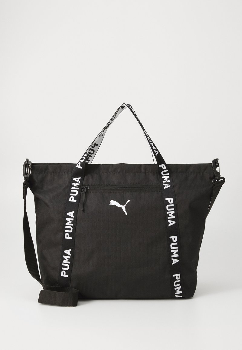Svart totebag med hvit Puma-logo og merkede stropper. Har en glidelås-lomme for oppbevaring. Ideell for uformell eller sporty bruk.